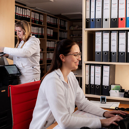 Zwei Mitarbeiterinnen der Neuen Apotheke vor Regalen mit Ordnern